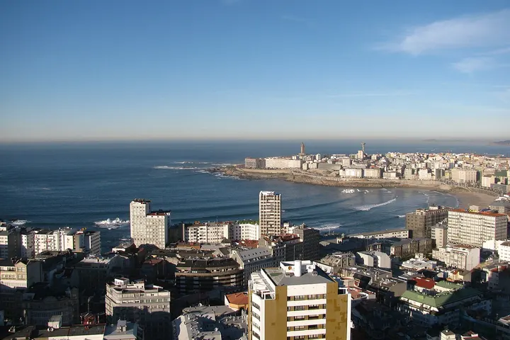 Un panorama urbano con edificios, una playa, el mar y el cielo azul en primer plano