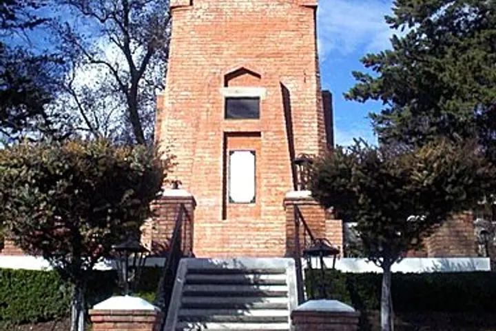 En primer plano, una torre de ladrillo rojo con escaleras de piedra y un reloj de sol