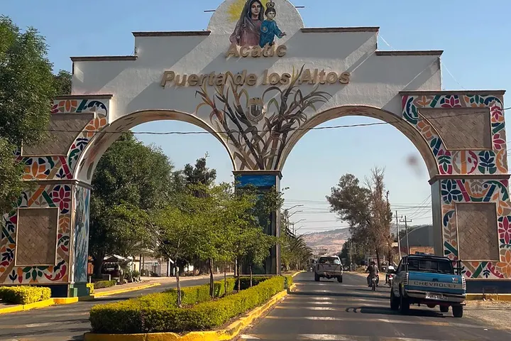 Un arco de entrada con una imagen de la virgen y el nombre de un pueblo en letras doradas