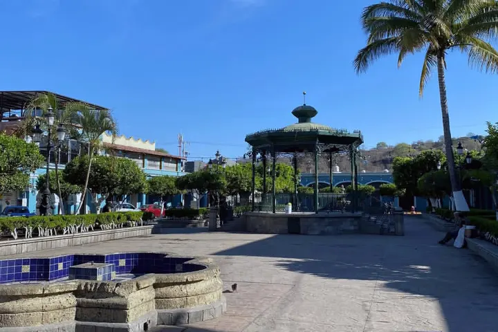 En primer plano, un pequeño estanque con un fuente y un kiosco en el fondo