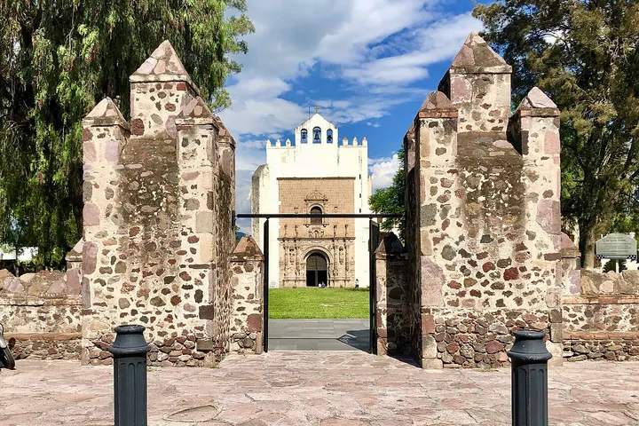 En primer plano, una puerta de piedra con dos torres laterales