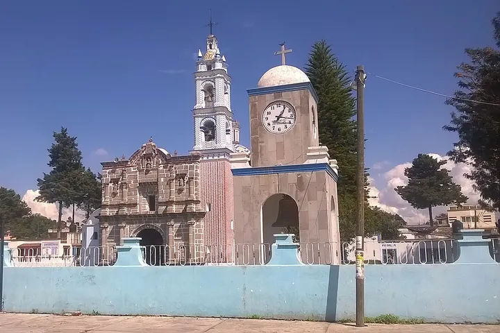 En primer plano, una iglesia con un reloj y una torre