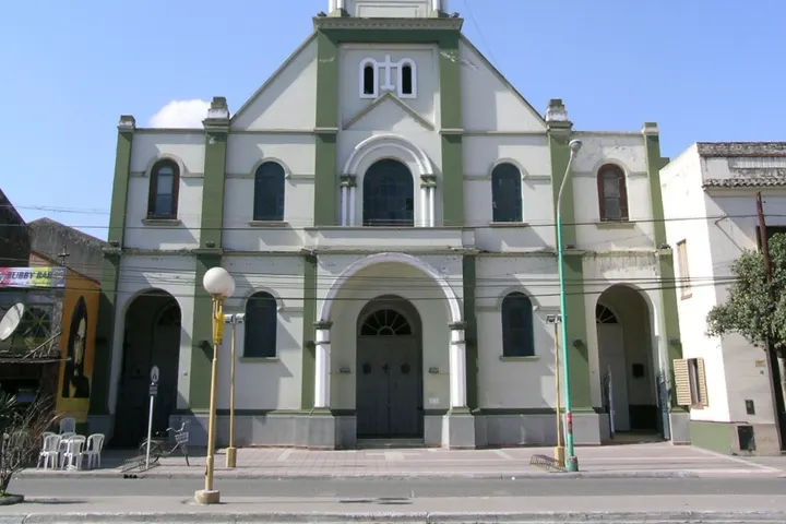 En primer plano, un edificio de estilo arquitectónico religioso, con un techo blanco y verde