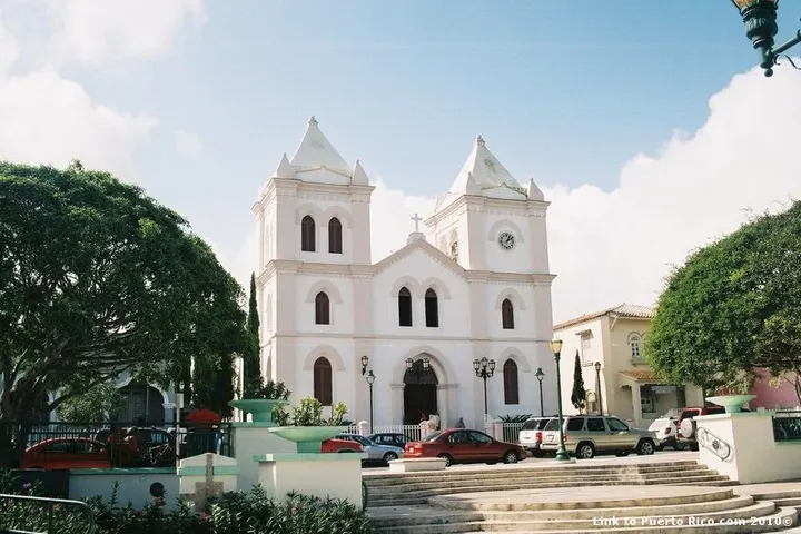 Un edificio blanco con dos torres, con una iglesia en primer plano