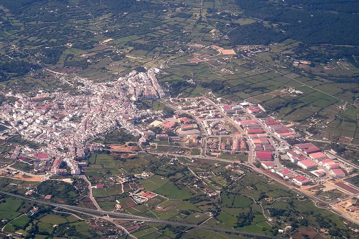 En primer plano, una gran fábrica con innumerables edificios de color rojo y blanco