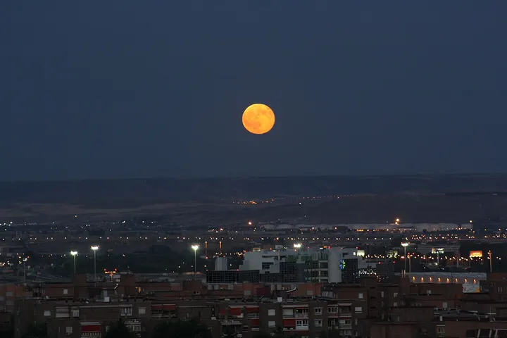 La luna llena se eleva sobre un edificio de apartamentos
