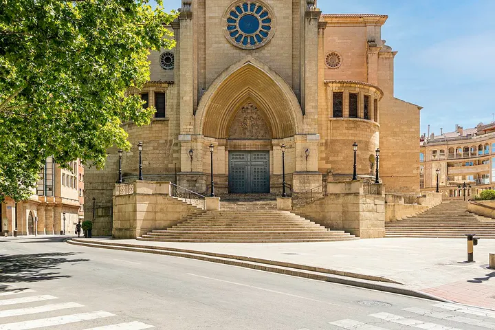 En primer plano, una iglesia de piedra con una gran puerta y escaleras que suben a ella