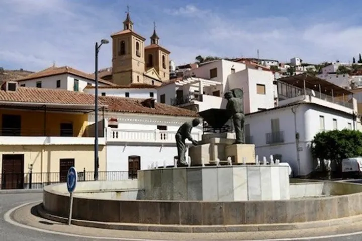 En primer plano, un monumento con un toro y un torero, en una plaza de una ciudad española