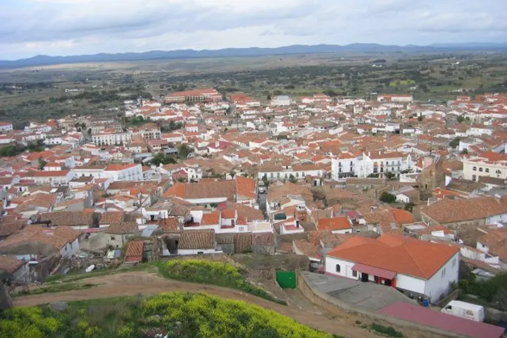 En primer plano, una granja con una casa blanca y un tejado rojo