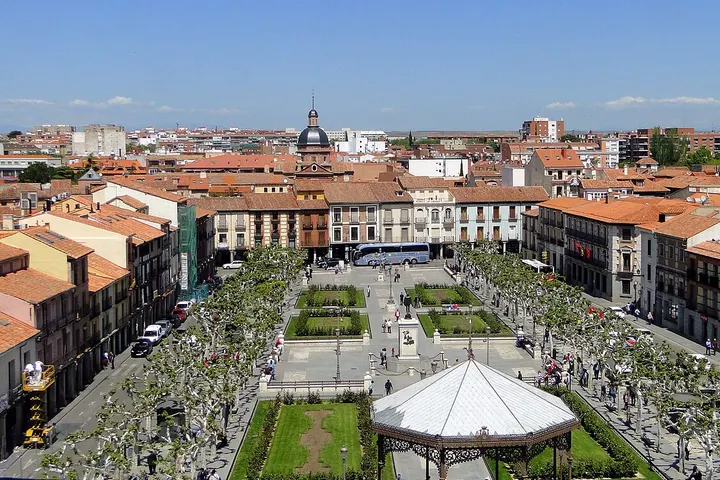 En primer plano, una plaza con un parque central, un kiosco y un edificio de arquitectura clásica