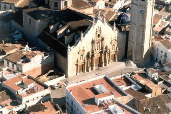 En primer plano, un edificio religioso con una torre y una fachada de estilo gótico