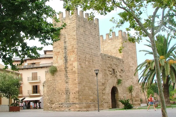 En primer plano, una torre de piedra con una puerta de arco y una torre de vigilancia