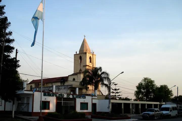 En primer plano, un edificio blanco con una bandera de Argentina