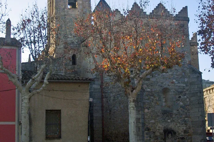 En primer plano, un edificio de piedra con una torre y una ventana redonda