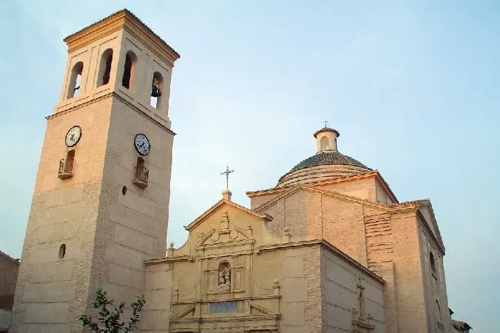 En primer plano, una iglesia con un campanario y una cruz
