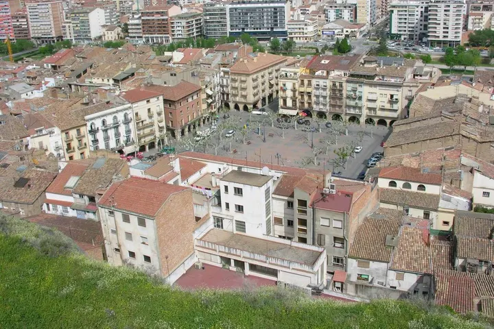 En primer plano, un gran edificio de color blanco con tejado rojo