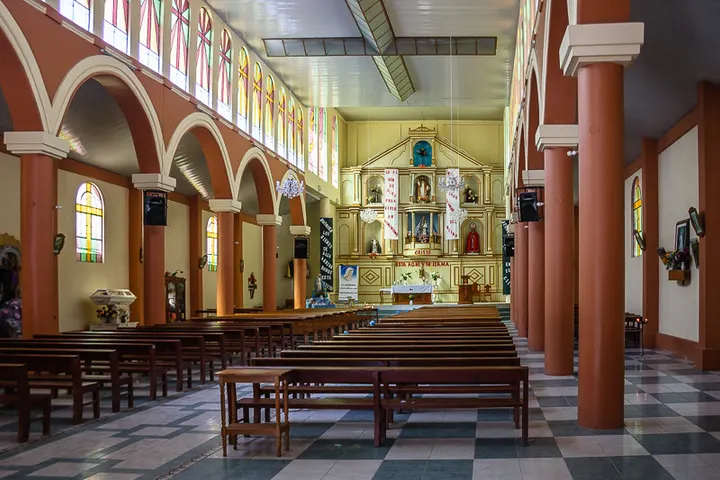 La iglesia presenta un interior con arcos, bancos y un altar