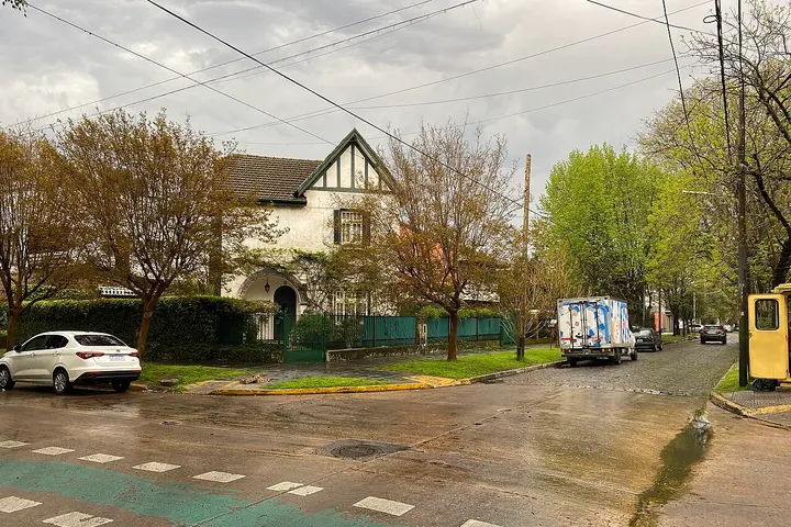 En primer plano, una casa blanca con techo de tejas y un camión de mudanzas
