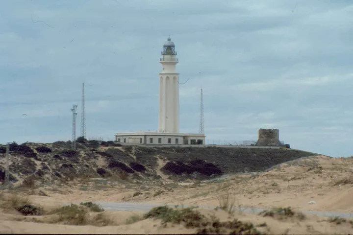 Un faro blanco con una torre alta y una casa blanca en primer plano