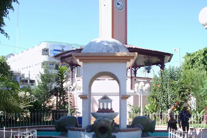 En primer plano, un hermoso y antiguo fuente de agua con un reloj en el centro