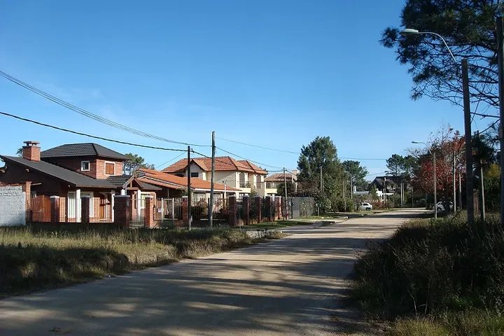 En primer plano, una calle con casas de ladrillo y techo rojo