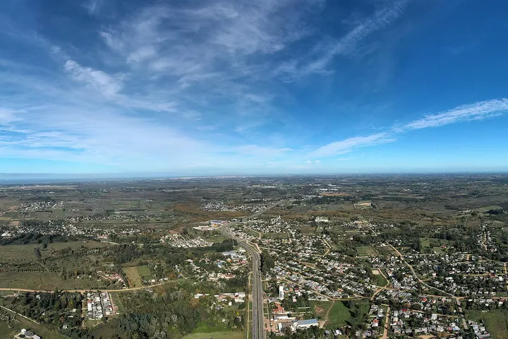 En primer plano, un gran parque con un camino de circunvalación que pasa por el centro