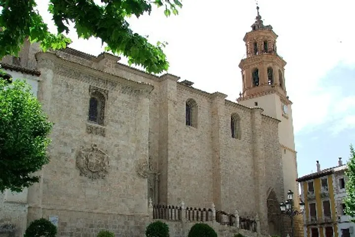 En primer plano, una iglesia con un campanario de piedra y una fachada de piedra blanca