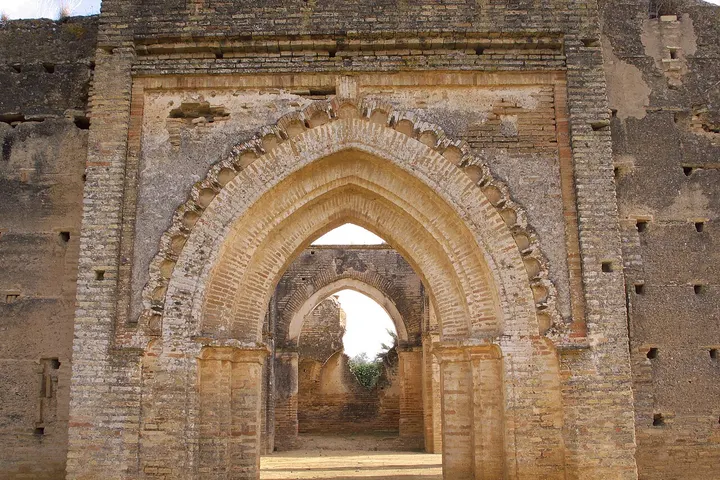 En primer plano, se ve una arquitectura antigua con arcos de piedra