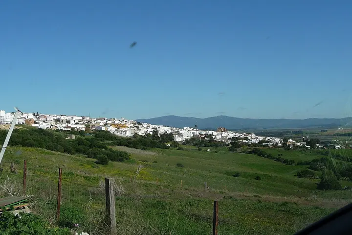 En primer plano, una valla de alambre de púas con postes de madera