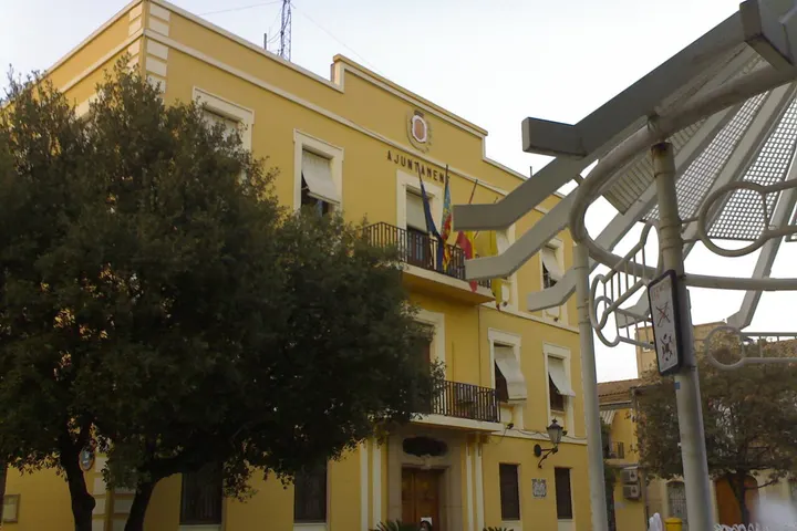 En primer plano, un árbol grande y una estructura metálica