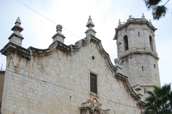 En primer plano, una iglesia blanca con un campanario