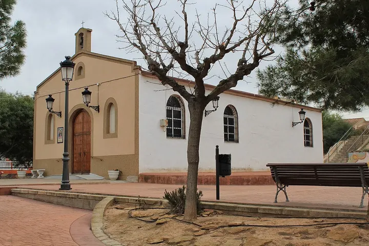 En primer plano, una iglesia con una puerta de madera y una torre de campanario