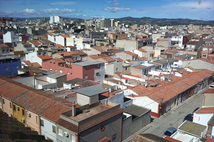 En primer plano, se ve una calle con casas de tejado rojo