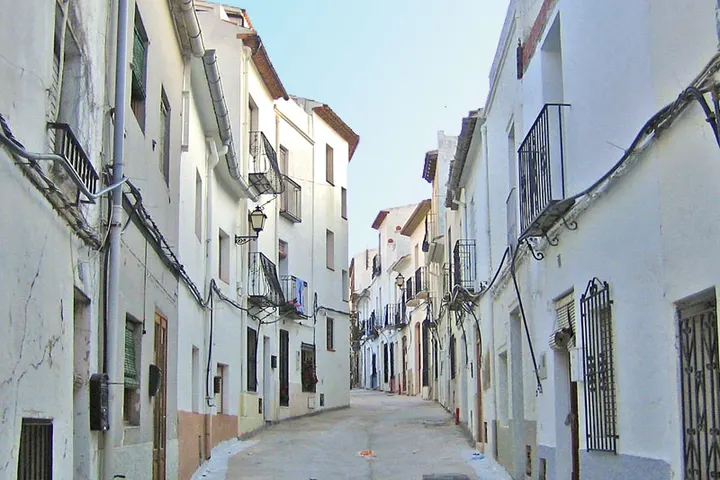Esta es una calle con edificios blancos y balcones
