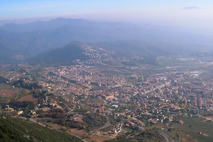 En primer plano, se ve una pequeña ciudad rodeada de montañas