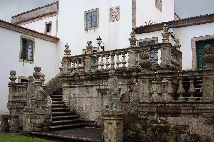 En primer plano, una escalera de piedra con estatuas de piedra de personas