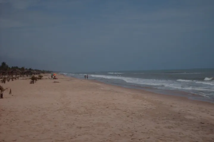 Una playa con una persona caminando por la orilla