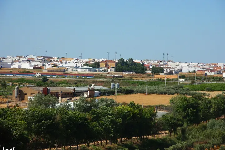 En primer plano, se ve una granja con un granero y una casa de campo