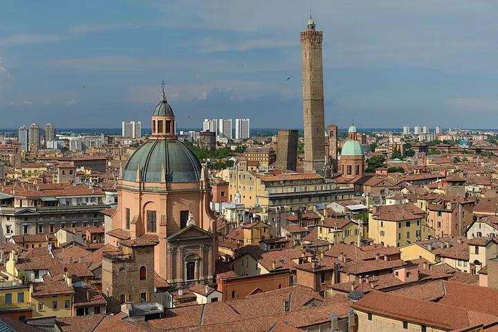 En primer plano, se ve una iglesia con una cúpula verde y una torre alta de piedra