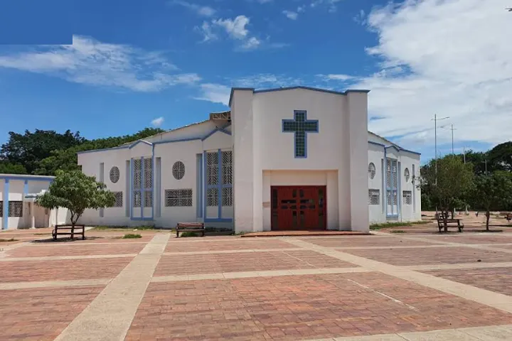 En primer plano, una iglesia blanca con una cruz azul en la fachada