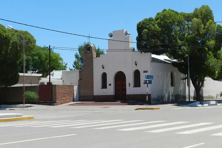En primer plano, un edificio blanco con arcos y una entrada roja