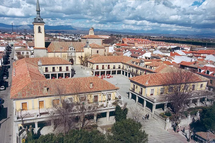 En primer plano, un edificio con un reloj de torre y una plaza con árboles sin hojas