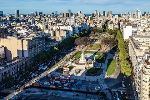 En primer plano, un parque con un monumento y un mercado