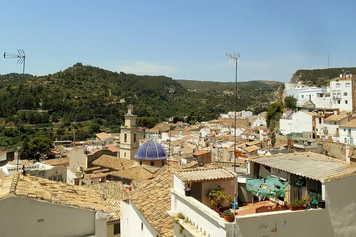 En primer plano, un edificio blanco con un patio cubierto