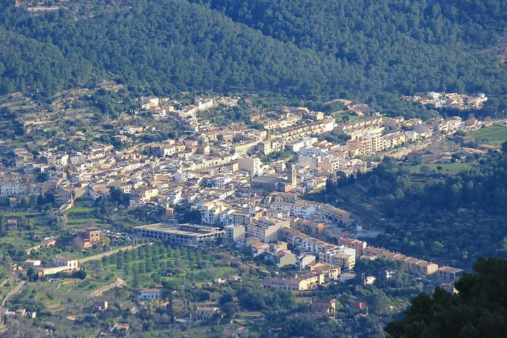 En primer plano, un gran estadio de fútbol se alza entre los edificios de una pequeña comunidad rural