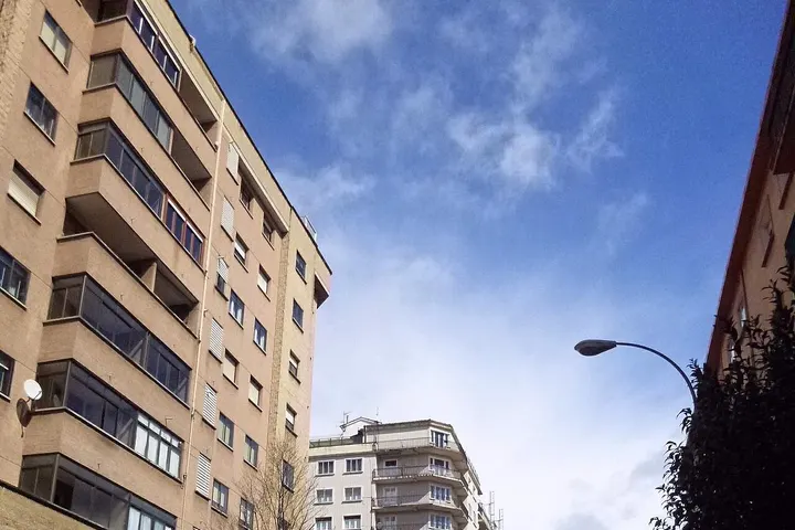 En primer plano, un edificio de apartamentos de color beige con balcones
