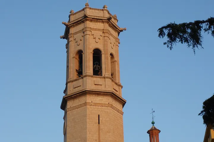 En primer plano, una torre de iglesia con un campanario de piedra