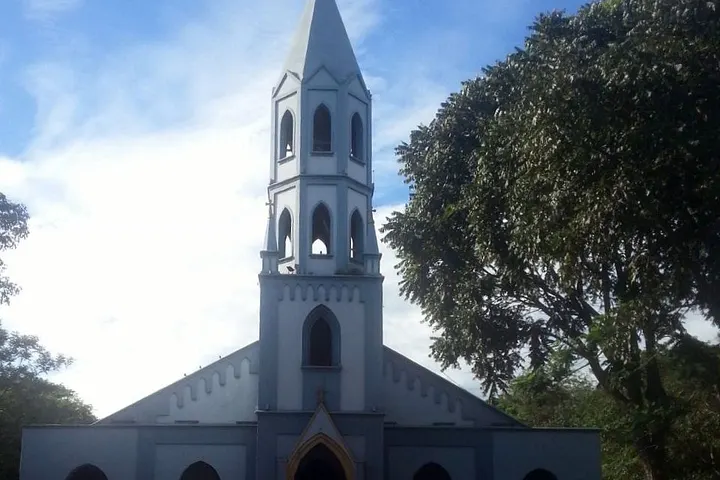 En primer plano, una iglesia blanca con una torre de campanario