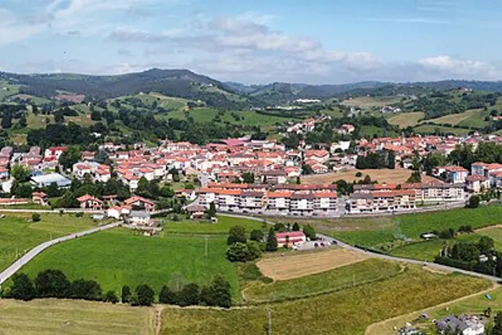 En primer plano se ve una granja con un granero y una casa de campo rodeada por campos de cultivo