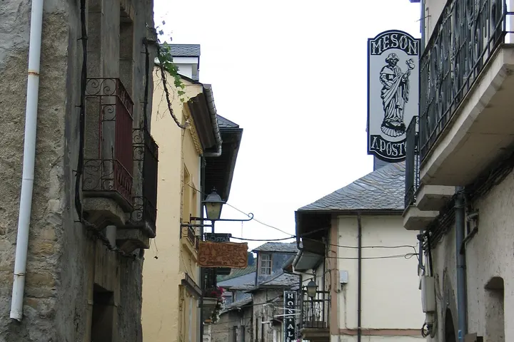 En primer plano, una pequeña tienda de postales, Meson, con una imagen de una mujer en el cartel